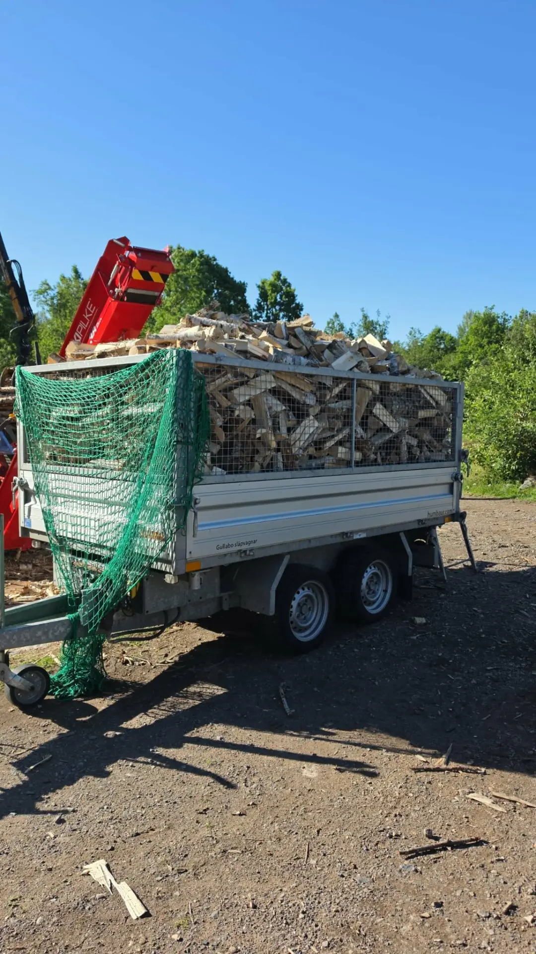 Släp lastat med kapad björkved för hemleverans